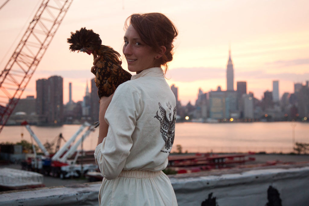 Annie Novak holding a chicken on her rooftop farm in Greenpoint, Brooklyn.